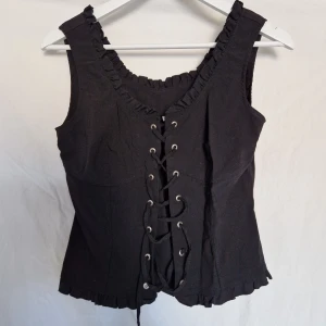 Korsett - Korsettopp i svart med justerbara band framtill. Strl 38 & mycket fint skick