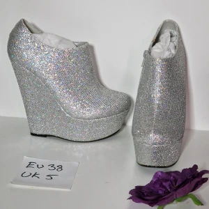 Partyklackar silver holo strl 38 - Supersnygga kilklackar som glittrar i regnbågens alla färger! Supersvårt att fånga deras fulla glittrighet på bild =/  Klackhöjd ca 15 cm Platå ca 5 cm  Skorna är nya och oanvända men har fläckar, lim som blivit gult syns mer på bild än i verkligheten.