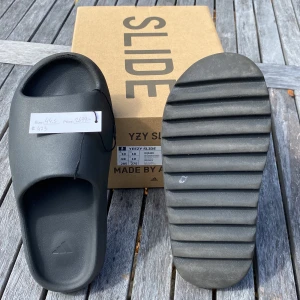 Yeezy Slides Onyx - Säljer Mina Yeezy Slides Köpta Ifrån Kicks N Stuff.  Dom är lite använda, under sidan är lite smutsig. Inköpta för 2700kr  men säljer dom för 1000kr. Boxen är perfekt och inga skador. Priset kan så klart diskuteras! Dom passar som 43-42