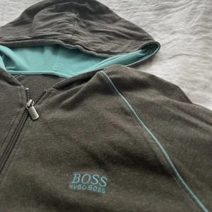 Hugo boss zip hoodie - Mörkgrå ziphoodie med blå luva från Hugo boss använd va 5ggr men används ej längre o därav säljs. Tröjan finns nästan ingenstans o köpa längre o pris går att diskutera
