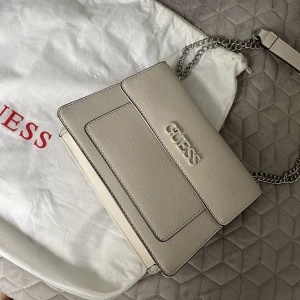 Beige guess väska - Säljer en väska från guess, den har används max en gång, så den är som ny. Har inga defekter eller märken. Nypris 1200 kr