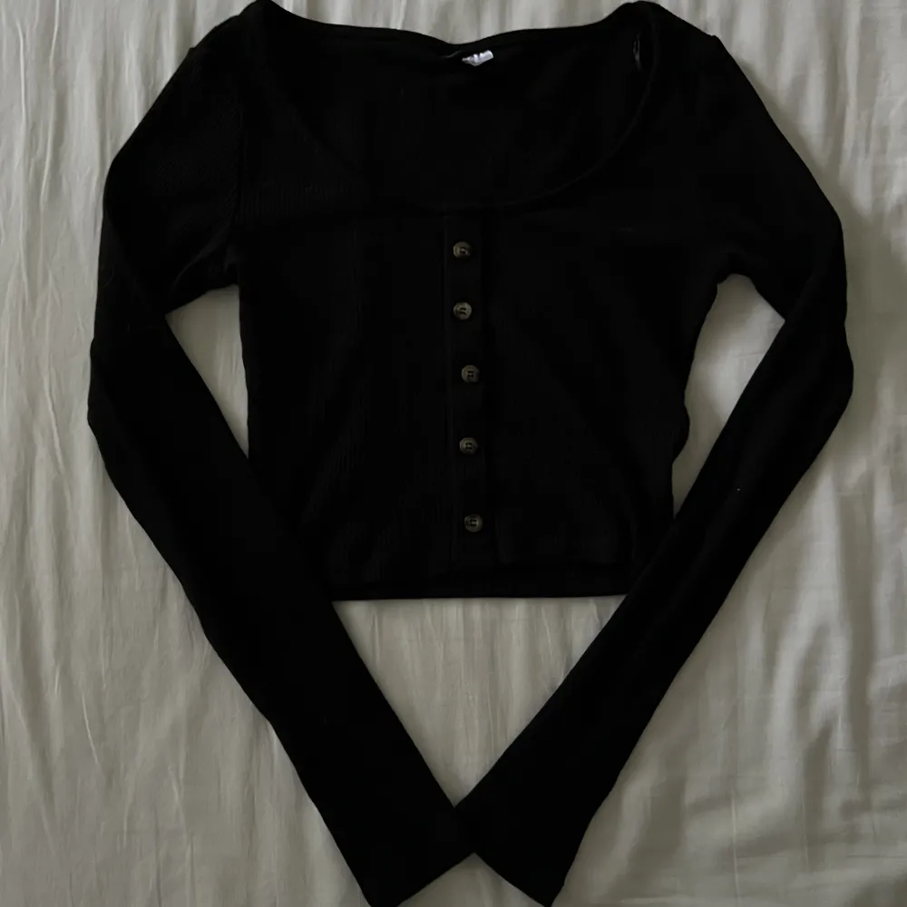 Supersöt croppad svart tröja med knappar (som inte går att öppna). Begagnat skick, men inga fläckar eller hål! Storlek XS men passar även S🫶💕. Toppar.