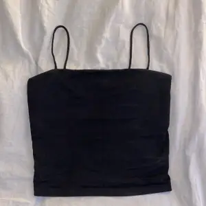 Ett svart basic ganska kort linne från Gina Tricot. Den är i använt skick men inget som syns förutom det lilla hålet i början av ena bandet. Det finns även ett extra tyg över bröstet under linnet!