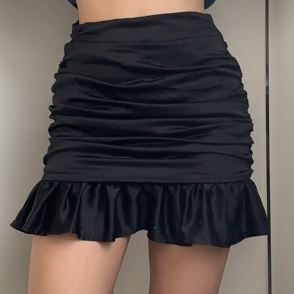 Svart ”siden”-kjol från Missguided i storlek 36. Volang nertill och dragkedja i sidan. Aldrig använd och i nyskick. . Kjolar.