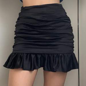 Svart ”siden”-kjol från Missguided i storlek 36. Volang nertill och dragkedja i sidan. Aldrig använd och i nyskick. 