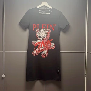 Philip Plein T-shirt/klänning  - Philip Plein klänning i T-shirt modell. Helt ny och aldrig använd, knappt provad. Tryck med rhinstones fram. Även tryck bak. Storlek M. Kan hämtas eller skickas.