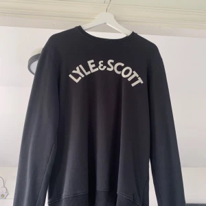 Lyle & Scott Tröja - En svart Lyle & Scott tröja i storlek S. Broderat märke på framsidan av tröjan. Passformen är dessutom normal