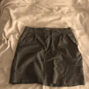 En grå kjol i mjukis material, en ficka på varje sida.