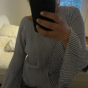 Randig knyttopp - Säljer denna fina toppen då den ej kommer till användning! Vida ärmar och knyte i ryggen, man kan även vända den och ha knytningen i fram, knuten sitter inte fast så man kan reglera storleken och knuten hur man vill! 150kr+frakt 