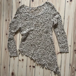 Väldigt söt topp - En fin topp i begie, spets/pärlor/blommor, lite sne på sidan som syns på bilden. Går ner över höften. Köpt 2hand och har hängt i min garderob sen dess så hoppas någon ny lycklig finnar denna och använder den. Väldigt fint skick!