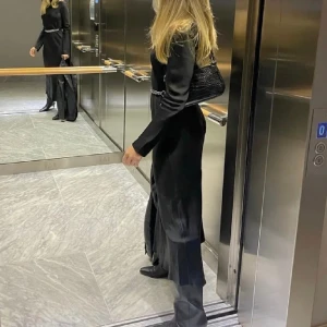 Svart satinklänning med skärp - Svart långärmad långklänning i satin med tillhörande silvrigt skärp från & Other Stories. Endast använd vid ett fåtal tillfällen och är utan defekter. Nypris 1395 kr.