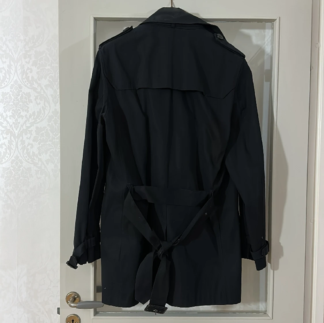 Fin svart kappa med bälte i midjan.  - 90