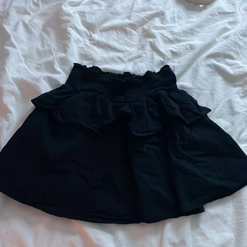 Kort svart kjol med volanger. Fungerar även som topp om man vill.. Kjolar.