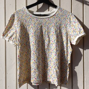Cropped T-shirt with a floral print - 100% cotton. Length 55 cm. Width between armpits 54 cm. The label says XXL, real size is around L.