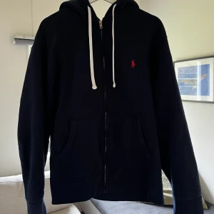 Ralph Lauren Zip-Hoodie - Säljer denna fräscha zip-hoodie från Polo Ralph Lauren då jag tröttnat på den. Mycket bra skick 9/10! Nypris: 1795 kr. Pris kan diskuteras. Garanterat äkta, kvittot finns. Frågor? Hör av dig!