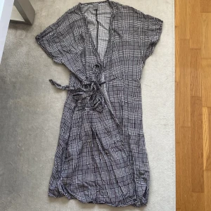 Rutig Omlottklänning - Rutig omlottklänning från Lindex. Slutar strax över knäna. Använt gott skick!