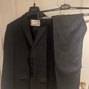 En jättefin svart kostym, från sandelins i mycket bra kvalite. Kavaj storlek 44 och byxorna S   Använd en gång. Nypris 3500