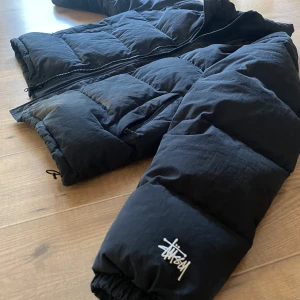 Stussy puffer jacket - Äkta Stüssy pufferjacka helt felfri, använd fåtal gånger. Storlek på lappen är XXL och den passar L-XXL. Sitter fint o fluffigt, väldigt varm perfekt till vintern! Hör av er vid frågor, fler bilder osv. Pris kan diskuteras, fraktar och möts upp i Sthlm! 🖤