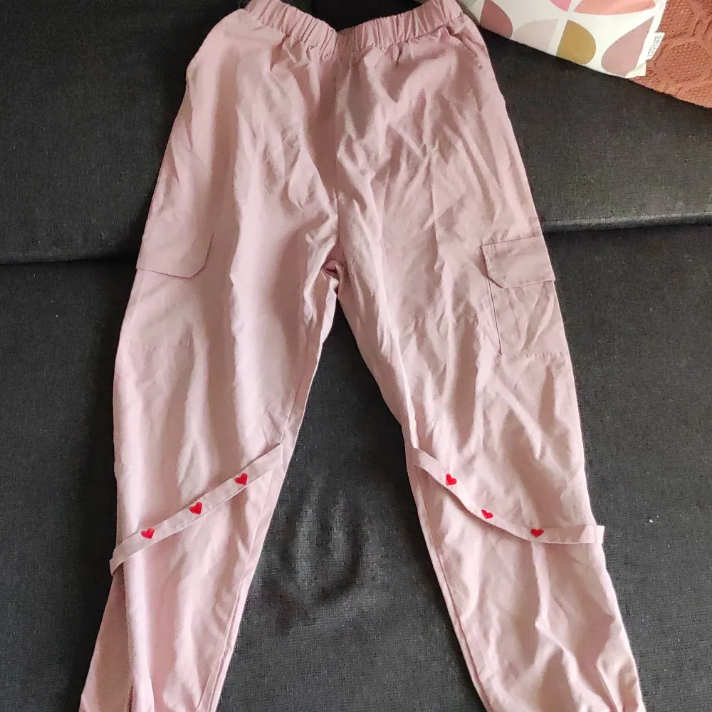 Helt nya och oanvända, rosa träningsbyxor med hängslen och små fickor.  Materialet är halt och tunt.. Jeans & Byxor.