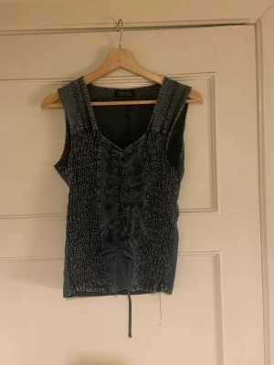 DENIM KORSETT - Mjuk denimkorsett som går att dra åt med snörena och knyta om man vill! Den är liksom inte i denim utan i ett mjukt material, och ”smockad” på sidorna som synes. Smiter åt kring kroppen bra! 