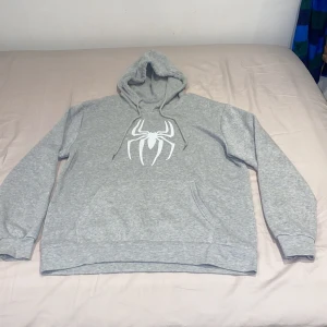 Ljusgrå Spiderman Hoodie  - En ljusgrå spiderman Hoodie, har används 2-3 gånger. Den har mjukt material inuti, materialet på hoodien är väldigt bra. 