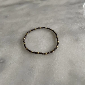 Brunt pärlarmband - Brunt pärlarmband med guldiga detaljer. 