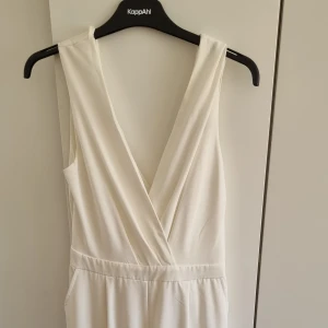 Vit jumpsuit fest - Vit jumpsuit med draperad öppen rygg i fint material. Från Naanaa, storlek M. Passar även S. Endast använd ett fåtal gånger.