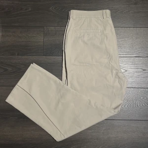 Beige chinos - Ett par beige chinos från dockers. Lite vidare, rak passform. Midjemått: 44cm; outseam: 101cm; Benöppning: 23.5cm. Hör gärna av dig om du undrar något!