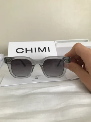 CHIMI 04 GREY - Säljer sjukt eftertraktade och trendiga solglasögon inför sommaren. Glajorna är i högsta toppskick utan tecken på användning. Köptes för 1250kr på NK. Medföljer gör: chimi 04 grey, box, fodral, kvitto, dustbag, putsduk (oöppnad) och tack kort. Skick:10/10