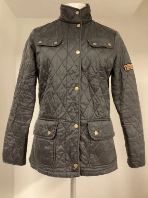 Barbour quiltad jacka  - Jättesnygg Barbour quiltad jack i väldigt fint skick. Svart färg. Storlek 40• Kika gärna på mina övriga auktioner. Skickar spårbart. Samfraktar för lägsta möjliga fraktkostnad.