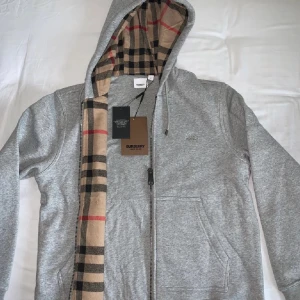 Burberry Hoodie - Grå Burberry hoodie. En av de mest eftertraktade klädesplaggen. Väldigt sällsynt, finns med etiketten kvar och dessutom bara använt ett fåtal gånger. Storlek L.  Nypris 7000kr. Släpper för 3200kr. 
