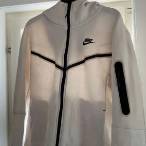 Nike tech - En beige Nike tech ziphoodie i stl S.Den är knappt använd och köpt från Nike. Köpte den för 1400kr o säljer den nu för 700 pga att den inte kommer till användning 