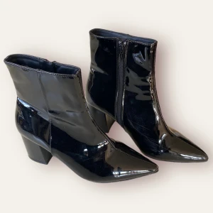 Svarta höga klackskor - Ett par svarta spetsiga klackskor i glansig plast. Knappt varit använda. I fint skick. Märket är Tiamo. För fler bilder kontakta mig :)