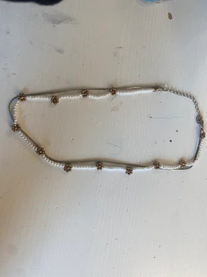 Guld halsband med blommor och pärlor - Ett guld halsband med 11 blommor och pärlor på. Perfekt för sommarn