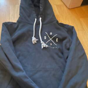 Säljer en svart hoodie från Dope med tryck både fram och bak. Den har en stor ficka framtill och justerbar huva med snören. Perfekt för en avslappnad stil!