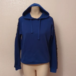 Blå hoodie från Whales Spirit - Säljer en snygg blå hoodie från Whales Spirit. Den har en cool detalj med svarta ränder längs ärmarna och en klassisk huva med dragsko. Perfekt för en avslappnad stil eller när du vill hålla dig varm och bekväm. 