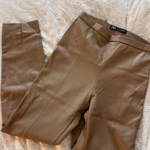 Zara skinnbyxor  - Skinnbyxor från Zara i en typ mörk beige eller ljus brun färg. Dragkedja på ena sidan för av och på tagning. Öppning på slutet på båda sidorna på baksidan 