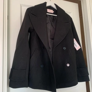 Svart kappa från Nelly - Säljer denna helt nya svarta kappan från Nelly då den inte passa mig så bra 💞 helt ny med prislappen kvar! Modellen heter ”warm peacoat” och den är köpt för 500 kr på rea ☺️ passar storlek xxs/xs 