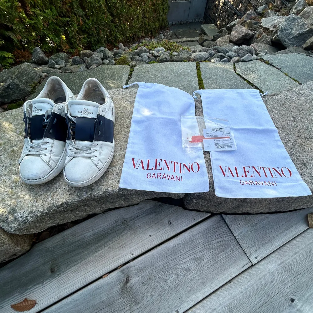 Säljer ett par vita Valentino Garavani sneakers med marinblåa detaljer. Skorna har en klassisk design.De är lite smutsiga men går och göra rent. Skick 6/10. Skorna är storlek 40 men passar även 41-41,5. Pris går och diskutera vid snabb affär.. Skor.