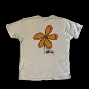 Stüssy flower tee - Smoke - Jättesnygg stüssy tshirt i beige. Den är knappt använd och har inga skador eller märken, materialet är mjukt och känns oanvänt. Tvättad ca 2 gånger. Köpt ny för 649kr. Skriv gärna om du har någon fundering..