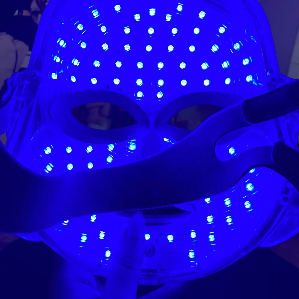 Säljer en LED-ljusbehandlingsmask som är perfekt för hudvård. Masken har olika ljusinställningar i rött, grönt och blått för att hjälpa till med olika hudproblem. Den är formad som ett ansikte och har justerbara remmar för att passa bekvämt. . Skönhet.