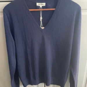 Mörkblå kashmirtröja från Soft Goat - Säljer en supermjuk och stilren mörkblå kashmir/merinoull tröja från Soft Goat. Den har en klassisk v-ringning och långa ärmar, perfekt för både vardag och lite finare tillfällen. Tröjan är i storlek S och aldrig använd.