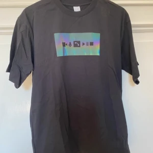 T-shirt - Säljer en svart t-shirt med tryck på. Tröjan är från Lindex och är i storlek 158/164. Den har aldrig kommit till användning.