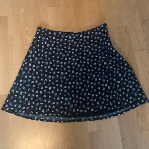 Svart kjol - Säljer då den börjar bli för liten för mig🩷Svart kjol med små blommor🌸Använd 2-3 ggr, inga defekter. 