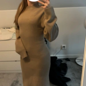 Beige/Brun stickad klänning - Säljer en superfin beige stickad klänning som är perfekt för höst och vinter. Den har en tight passform som framhäver figuren och långa ärmar som håller dig varm. Klänningen är i nyskick och passar perfekt för både vardag och festliga tillfällen.