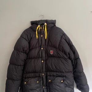 Fjällräven Expedition Down Jacket - En svart Fjällräven Expedition Down Jacket Storlek M Fint skick då den ä sparsamt använd. Finns en lagning på vänster ärm(se bild 3) och de vita detaljerna vid snörena är något slitna(se bild 4). Men detta är inget som syns i helhet. 4000kr priset är