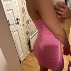 Rosa tight klänning - Säljer en superfin rosa klänning som är perfekt för fest! Den är tight och axelbandslös, vilket ger en snygg och stilren look. Klänningen är kort och sitter som en smäck. Perfekt för sommarens alla fester!