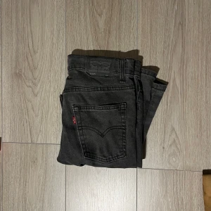 Svarta jeans från Levi's - Snygga svarta jeans från Levi's med klassisk femficksdesign och röd etikett på bakfickan. Perfekta för en stilren look. Passar till många olika outfits. 