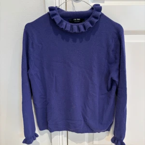 Lila cashmeretröja från Lisa Yang - Säljer en snygg lila tröja från Lisa Yang i storlek M (motsvarar 13-15 år). Tröjan har långa ärmar och en unik volangdetalj vid halsen och ärmsluten. Perfekt för att ge din outfit en färgklick!