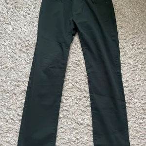 Mörkgröna byxor från Dressmann - Snygga mörkgröna byxor från Dressmann i regular fit. Tillverkade av 98% bomull och 2% elastan för en bekväm passform. Perfekta för en stilren look. Använd 2 gånger.